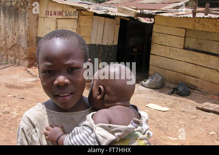 Kampala, Uganda-09 Aprile 2007: il ragazzo è caruing suo fratello più piccolo nella parte anteriore del suo villaggio vicino alla città di Kampala. Foto Stock