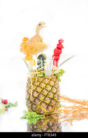 Ananas decorate con diversi di frutta e verdura sulla superficie specchiante. Sfondo bianco. Foto Stock