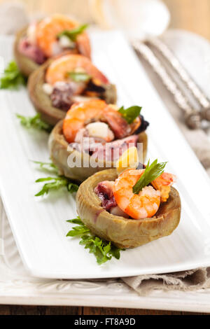 Cuori di carciofi farciti con frutti di mare. Sulla piastra bianca. Foto Stock