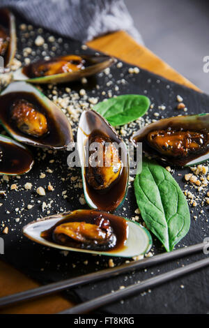 Piatto asiatico - le cozze in sticky salsa dolce, con arachidi e spinaci Foto Stock