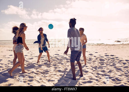 Ritratto di gruppo di amici felice avendo divertimento sulla spiaggia e gioca con la palla su un giorno d'estate.