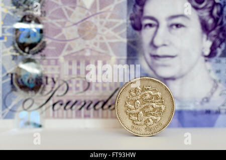 Una sterlina moneta con venti libbre banconota dietro Foto Stock