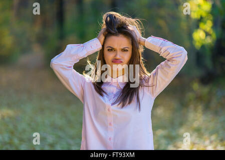 Una graziosa adolescente simpatiche ragazza sta tenendo la testa con le mani come la sua vita è piena di problemi diversi. Foto Stock