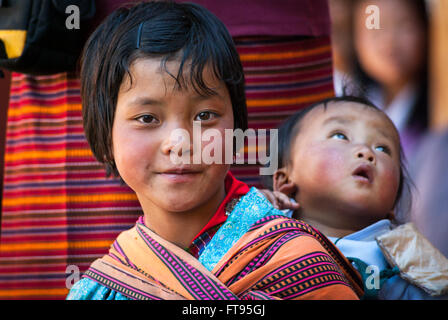 Una giovane ragazza Bhutanesi che porta un bambino in uno scialle sulla schiena a Gangte nella valle di Phobjikha, Bhutan Foto Stock