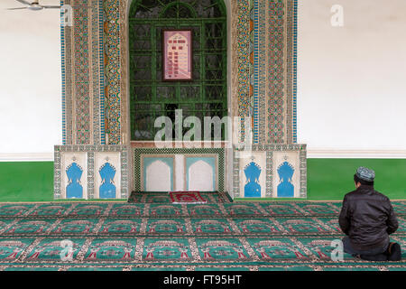 Un uomo che prega nel più grande in Cina alla Moschea Id kah di Kashgar city Foto Stock