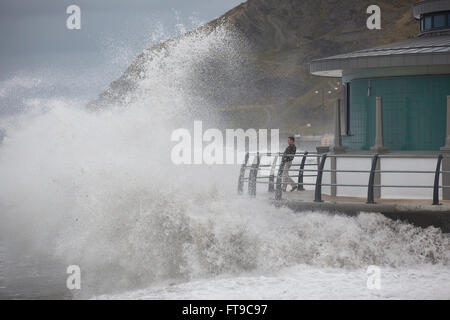 Aberystwyth, Wales, Regno Unito. Il 26 marzo 2016. Un umido molto Bank Holiday weekend. Come le onde si infrangono sulla nuova bandstand a Aberystwyth, vacanzieri a guardare, ignaro delle potenziali pericoli. Credito: Alan Hale/Alamy Live News Foto Stock