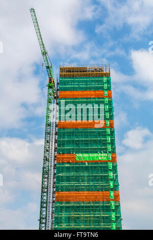 Sito in costruzione di un edificio alto, grattacielo, numerate pavimenti, tarp intorno all'edificio, Foto Stock