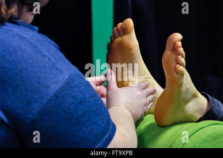 Lisburn, Irlanda del Nord. 25 mar 2016 - Un reflexologist tratta un paziente mediante sfregamento del meridiano di linee di energia per la pianta dei suoi piedi Foto Stock