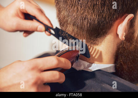 Professional barbiere il taglio di capelli del suo cliente Foto Stock