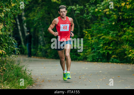 Di mezza età atleta corre attraverso il parco durante la maratona di Chelyabinsk Foto Stock