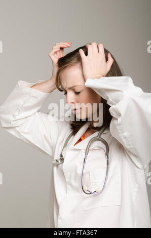 Frustrati medico donna in testa le mani Foto Stock