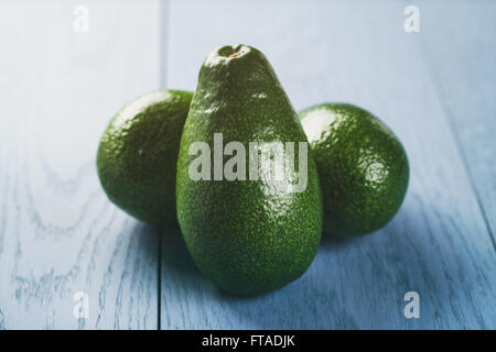 Tutto mature verde avocado su tavola di legno Foto Stock