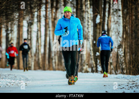 Ekaterinburg, Russia - 14 Novembre 2015: un uomo di mezza età runner corre sulla strada parco innevato durante Urban winter marathon Foto Stock