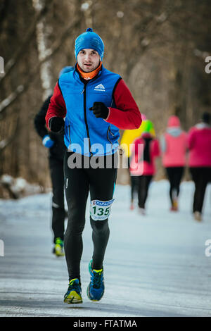 Ekaterinburg, Russia - 14 Novembre 2015: il giovane atleta maschio vestita per l'inverno corre nei boschi di distanza competitiva Foto Stock