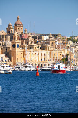 La vista di edifici storici di Birgu attraverso il Dockyard Creek con crociere nave passando lungo la costa di Malta. Foto Stock