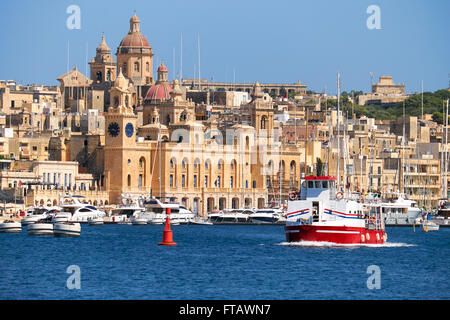 La vista di edifici storici di Birgu attraverso il Dockyard Creek con crociere nave passando lungo la costa di Malta. Foto Stock