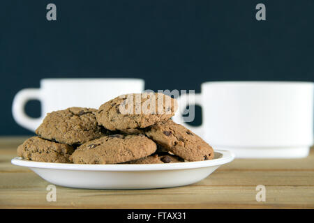 Biscotti al cioccolato e due tazze di tè su un tavolo di legno Foto Stock