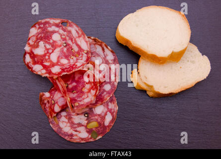 Fette di salame con pistacchi sulla sommità di ardesia viste superiore Foto Stock