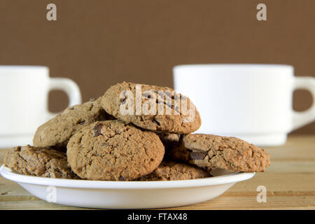 Biscotti al cioccolato e due tazze di tè su un tavolo di legno Foto Stock