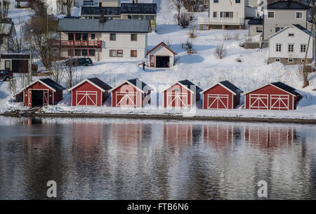 Barca Rossa con case a lato di un fiordo vicino a Tromso, Norvegia. Foto Stock