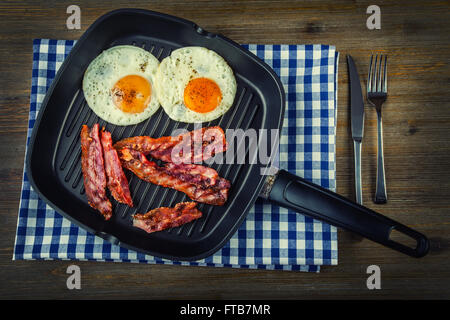 Prosciutto e uova. Uova e pancetta. Uovo salato e cosparsi di pepe nero. Prima colazione inglese. Bacon arrosto, due uova in padella Foto Stock