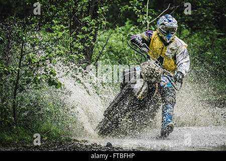 Motocross driver sotto la spruzzatura di acqua compete durante la gara di coppa di Ural di Enduro Foto Stock