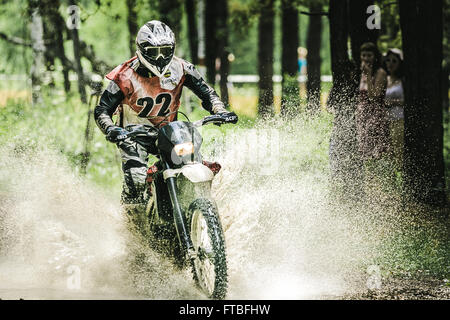 Motocross driver sotto la spruzzatura di acqua durante la gara di coppa di Ural di Enduro "cintura tono 2015' Foto Stock