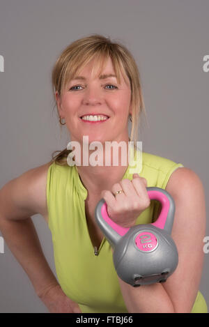 Donna che esercitano con un bollitore peso della campana del peso di 2 Kg Foto Stock