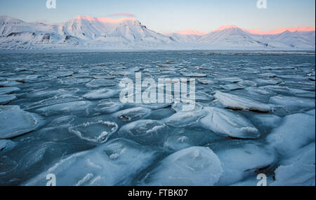 Tramonto litorale congelati a Sjøskrenten spiaggia con vedute Hiorthfjellet, Longyearbyen, Spitsbergen, Svalbard. Foto Stock