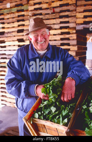 Ritratto del maschio sorridente contadino con prodotti freschi nel fienile Foto Stock