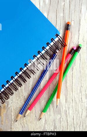 Notebook e matite colorate su di un tavolo di legno Foto Stock