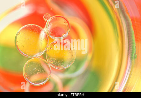 Gocce di olio su una superficie di acqua con colori in background Foto Stock