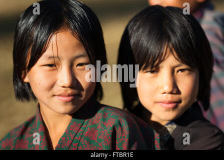 Due giovani ragazza bhutanesi amici indossando il tradizionale kira (wrap lungo abito) e giacca in villaggio Nimshong, southern Bhutan Foto Stock