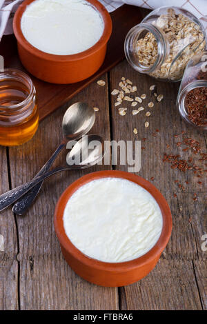 Fatto in casa lo yogurt greco in pentola di creta come tradizionale con miele,i fiocchi d'avena e semi di lino Foto Stock