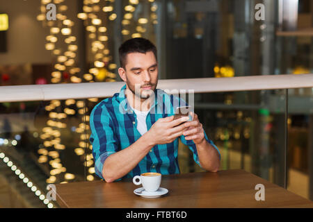 Uomo con lo smartphone e caffè presso il ristorante Foto Stock
