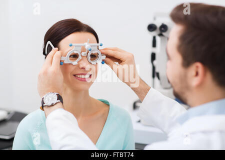 Ottico con telaio di prova e paziente presso la clinica Foto Stock