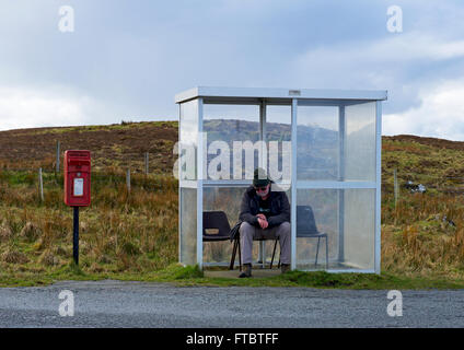 Senior uomo in attesa in bus rurale rifugio sull'Isola di Skye in Scozia UK Foto Stock