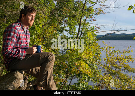 Un uomo di bere il caffè e guardare fuori sul fiume Hudson da Camp Morris Norrie, New York Foto Stock