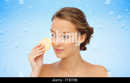 Giovane donna faccia pulizia con spugna esfoliante Foto Stock