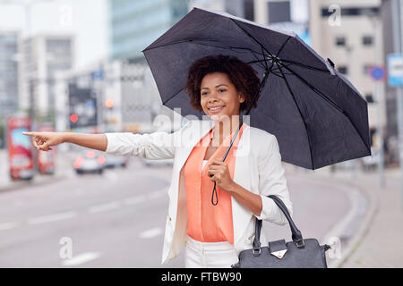 Felice donna africana con ombrello cattura di taxi Foto Stock