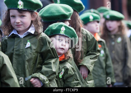 Falls Road, Belfast, Regno Unito 27 marzo 2016 una giovane ragazza che indossa un berretto verde con la Pasqua Lilly pop la sua testa fuori tra gli altri bambini alla sollevazione di Pasqua centenario Parade Credito: Bonzo Alamy/Live News Foto Stock