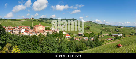 Il piccolo borgo medievale di Barolo e il verde delle colline e vigneti sotto il cielo blu in Piemonte, Italia settentrionale (panorama). Foto Stock