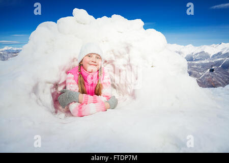 Felice ragazza in rosa usura posa in opera in corrispondenza del manto nevoso igloo Foto Stock