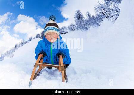 Little Boy in montagna scorrere sulla slitta Foto Stock