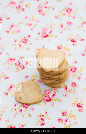 Una pila di a forma di cuore i cookie su uno sfondo floreale. Foto Stock