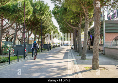 Comacchio, 12 marzo 2016 - un ciclista pedala sulla alberata waterfront promenade del lungomare italiano del Lido delle Nazioni Foto Stock