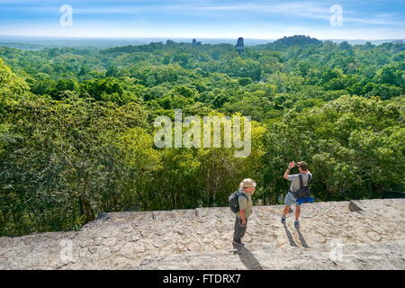 I turisti sulla sommità del tempio IV, le antiche rovine Maya, il Parco Nazionale di Tikal, Yucatan, Guatemala Foto Stock