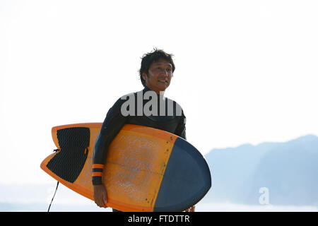 Surfista giapponese di camminare sulla spiaggia Foto Stock