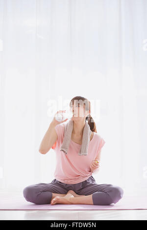 Giovane donna giapponese acqua potabile dopo la pratica dello yoga Foto Stock