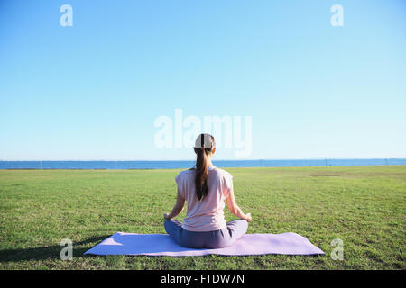 Giovane donna giapponese la pratica dello yoga in un parco della città Foto Stock